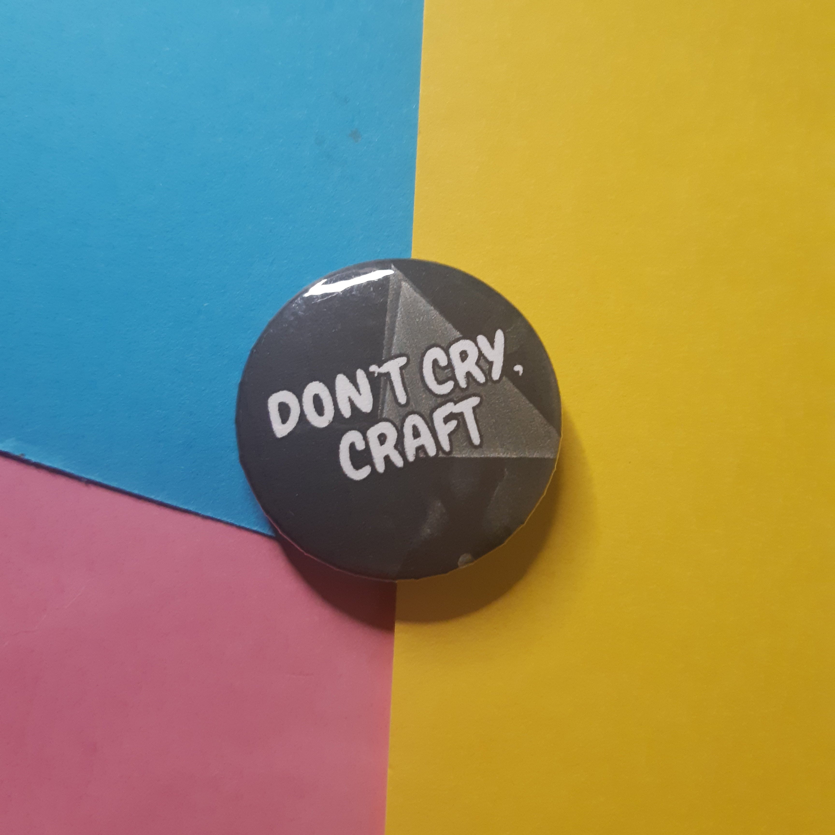 A round pin badge with the text 'DON'T CRY. CRAFT.