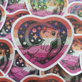 A heart-shaped sticker featuring a pokemon character against a pink, purple, and black patterned background, surrounded by other overlapping heart-shaped stickers.