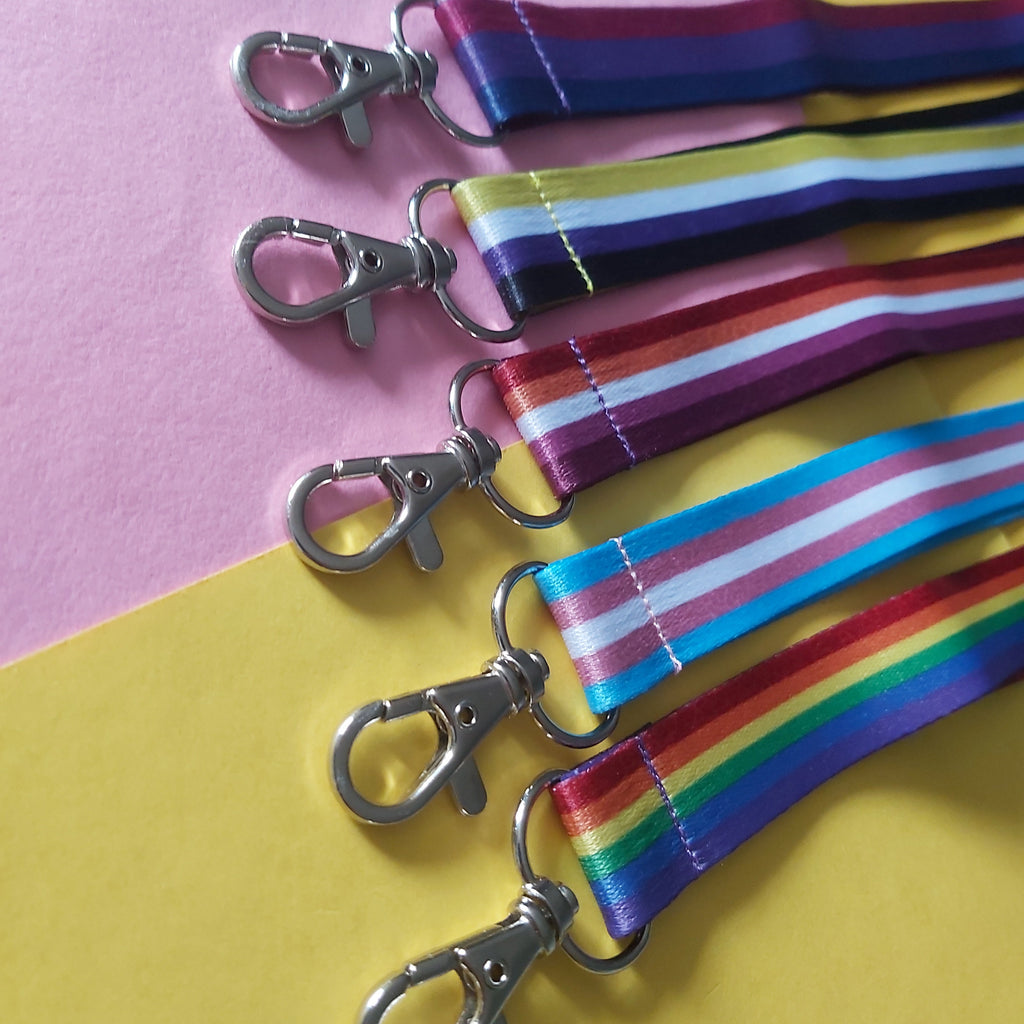 Five cotton lanyards with silver lobster clasps, arranged diagonally on a split pink and yellow background.