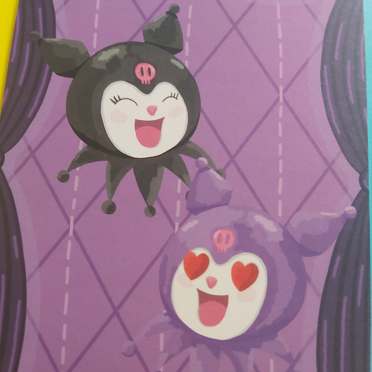 A close-up of a purple print featuring cartoon character Kuromi: one black character with a pink skull emblem and one purple character with red hearts, set against a purple diamond-patterned background with dark curtain-like shapes at the sides.