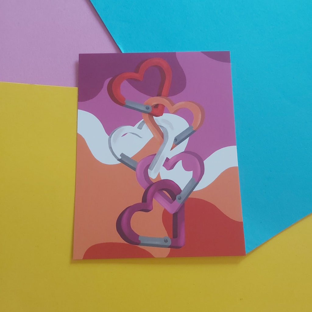 An art print featuring a stylised illustration of five interlocking heart-shaped carabiners in shades of orange, pink, and white, displayed on a colourful background of yellow, pink, and blue paper.
