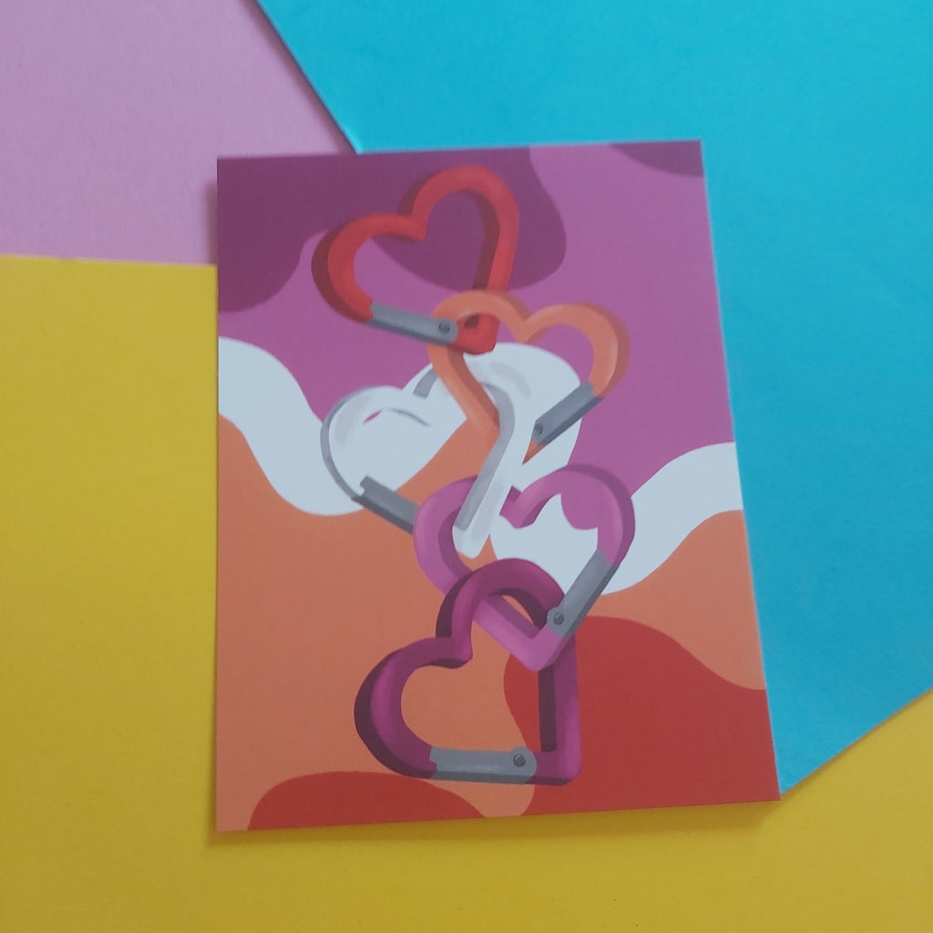 An art print featuring a stylised illustration of interlocking hearts in shades of pink, red, and orange, displayed on a colourful background of yellow, pink, and blue paper.