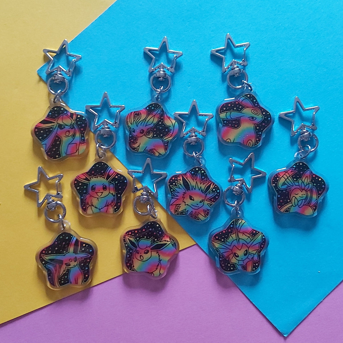 A set of colourful star-shaped charms, displayed on a background of yellow, blue, and purple paper.