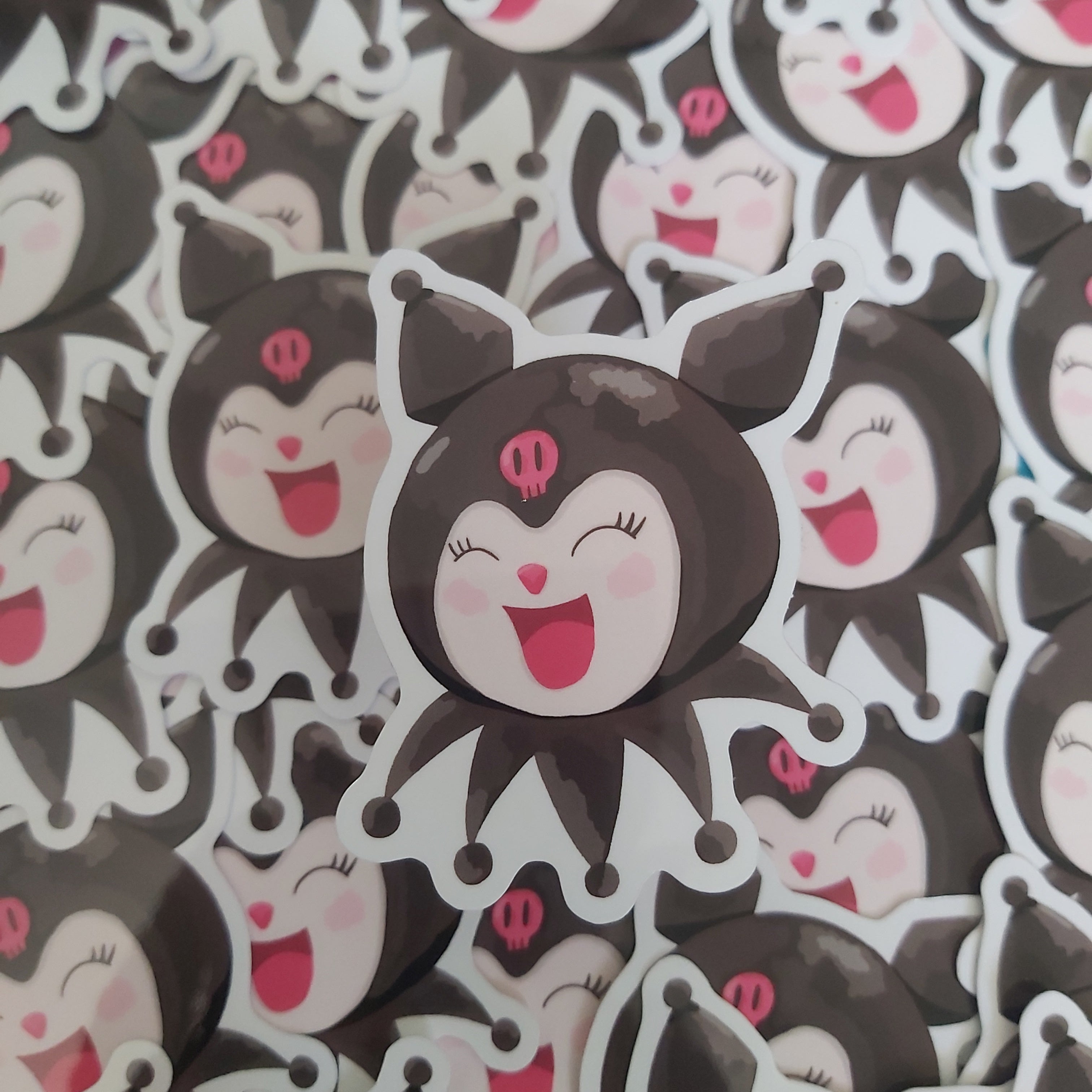 A close-up of multiple cartoon character stickers featuring Kuromi, the Sanrio character with a white face, pink mouth, and a small pink skull on the forehead, arranged closely together.