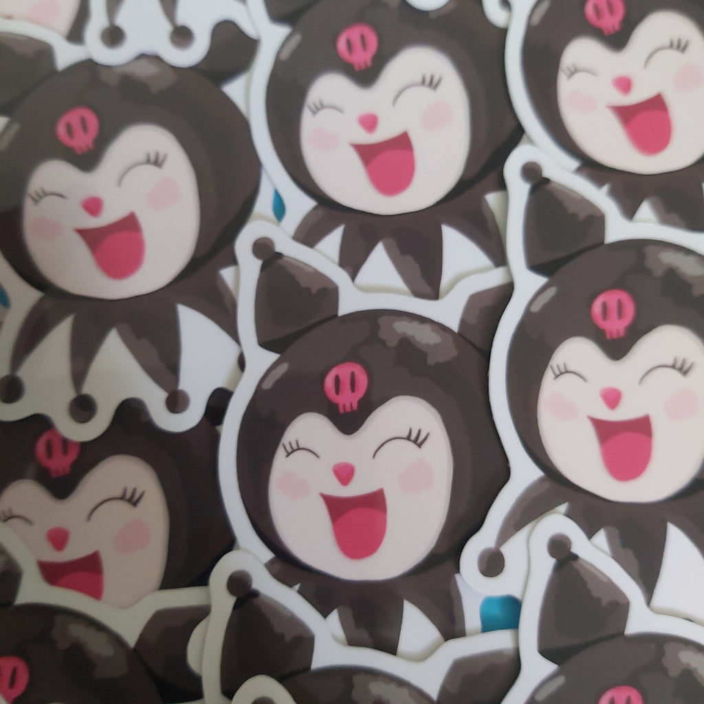 A close-up pile of cartoon character stickers featuring a black and white character with pink details and a smiling face.