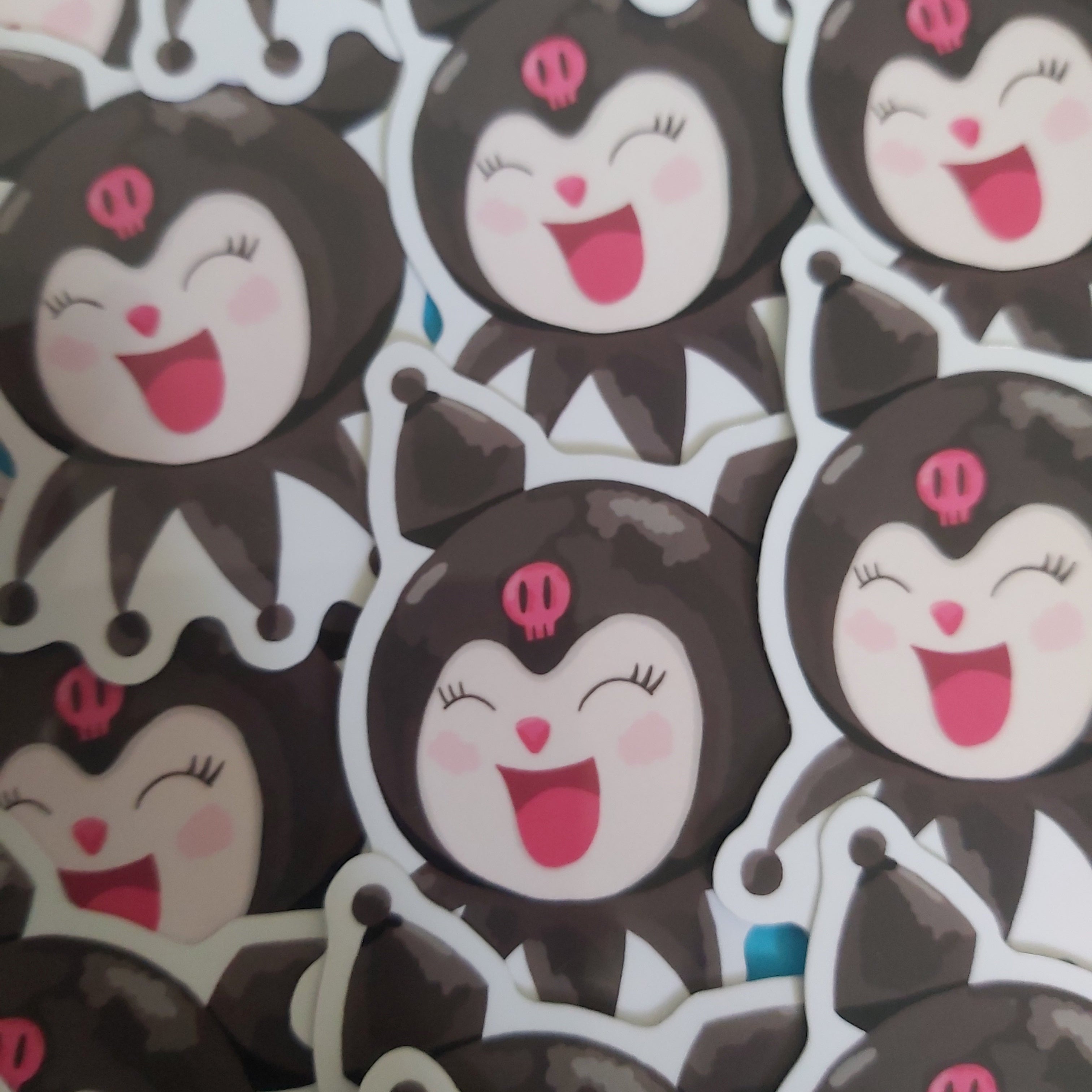 A close-up pile of cartoon character stickers featuring a black and white character with pink details and a smiling face.