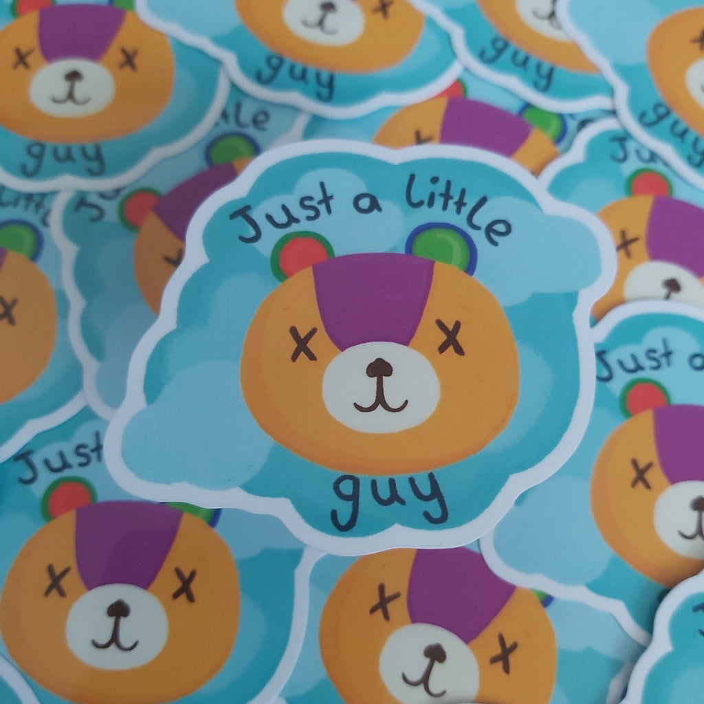 A close-up of multiple die-cut stickers featuring a cartoon bear face with the phrase 'Just a little guy' on a light blue cloud-shaped background.