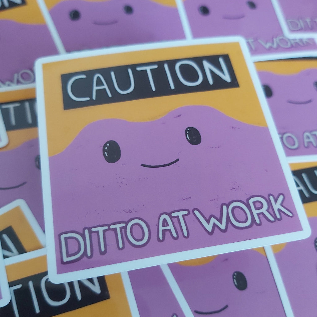 A close-up of a square sticker featuring a purple cartoon face with the text 'CAUTION' at the top and 'DITTO AT WORK' at the bottom, surrounded by other similar stickers.
