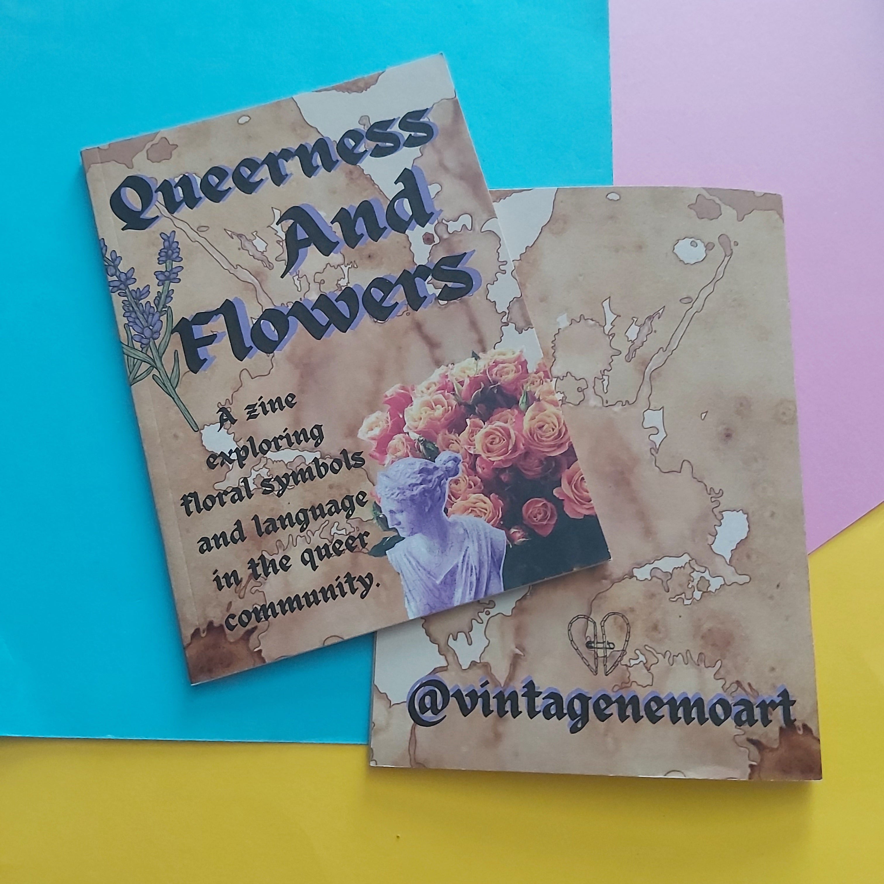 Two printed zines laid on a colourful background. The left is the front cover, which reads 'Queerness And Flowers' with decorative text and a floral illustration; the right shows the back cover shows a tea-stain-style design with '@vintagemoart' and a small heart logo.