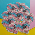A cluster of die-cut stickers featuring stylised pink and blue roses with black outlines, arranged on a background of bright yellow, pink, and blue paper.