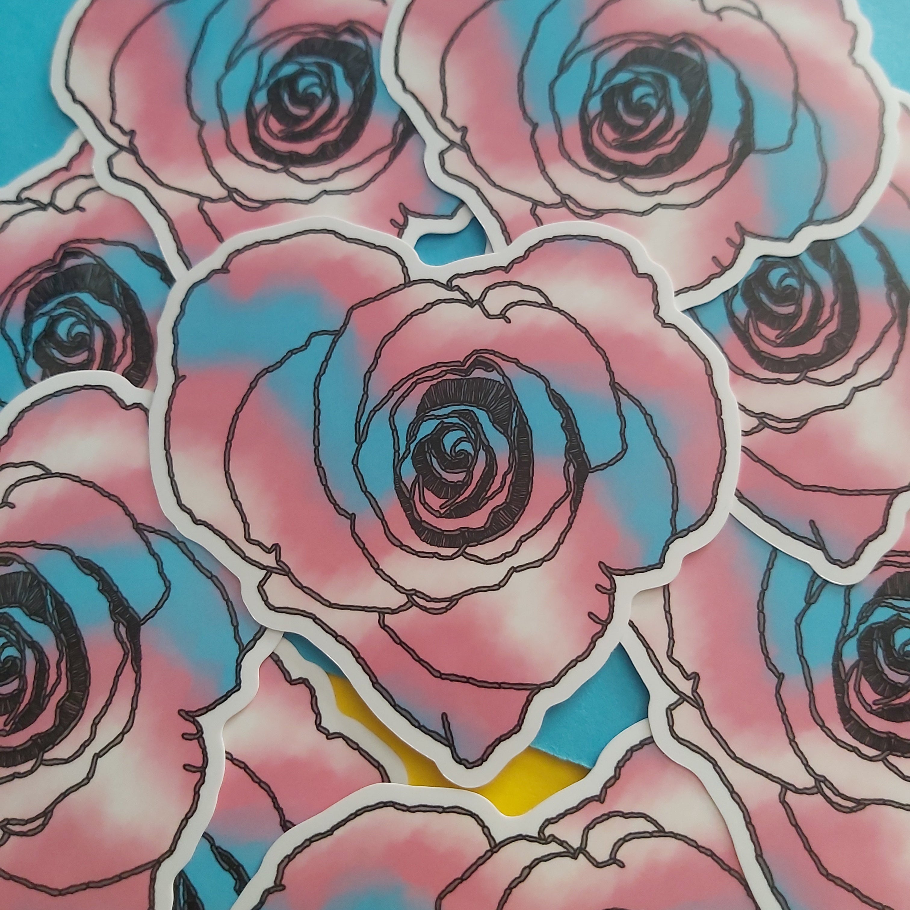 A close-up of multiple die-cut stickers featuring stylized pink and blue roses with black outlines, arranged on a bright blue background.