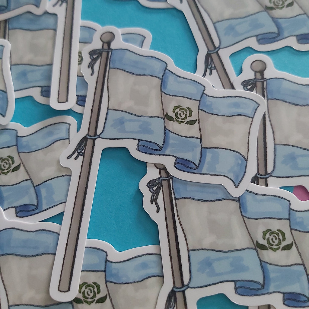 A close-up of multiple die-cut stickers featuring illustrated Achillean flags on poles, arranged overlapping on a bright turquoise background.
