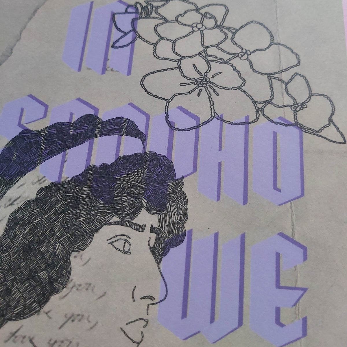A close-up of a print featuring stylised purple text, a line drawing of flowers, and a profile sketch of a woman on a beige background.