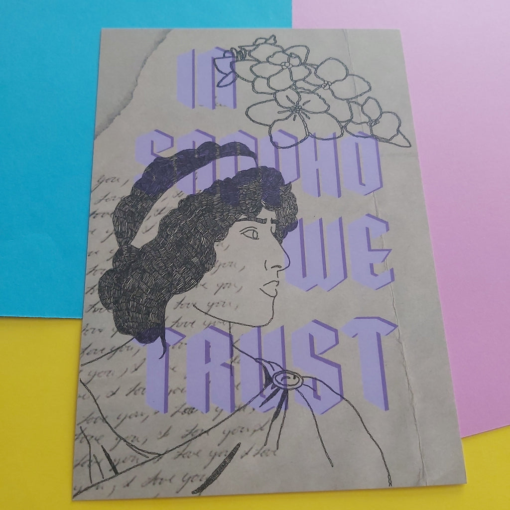 An art print featuring a black ink sketch of a woman's profile with flowers above her head, overlaid with large lavender-purple text reading 'IN SAPPHO WE TRUST' on a beige background. The print is photographed on a colourful surface divided into cyan, pink, and yellow sections.