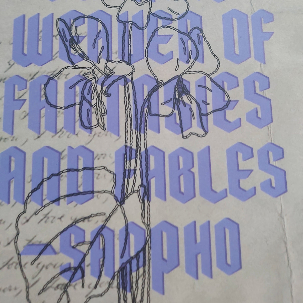 A close-up of a print design featuring large lavender text reading 'Love is a cunning weaver of fantasies and fables -Sappho' over a cream background, with a black line drawing of a flower and leaf motif.