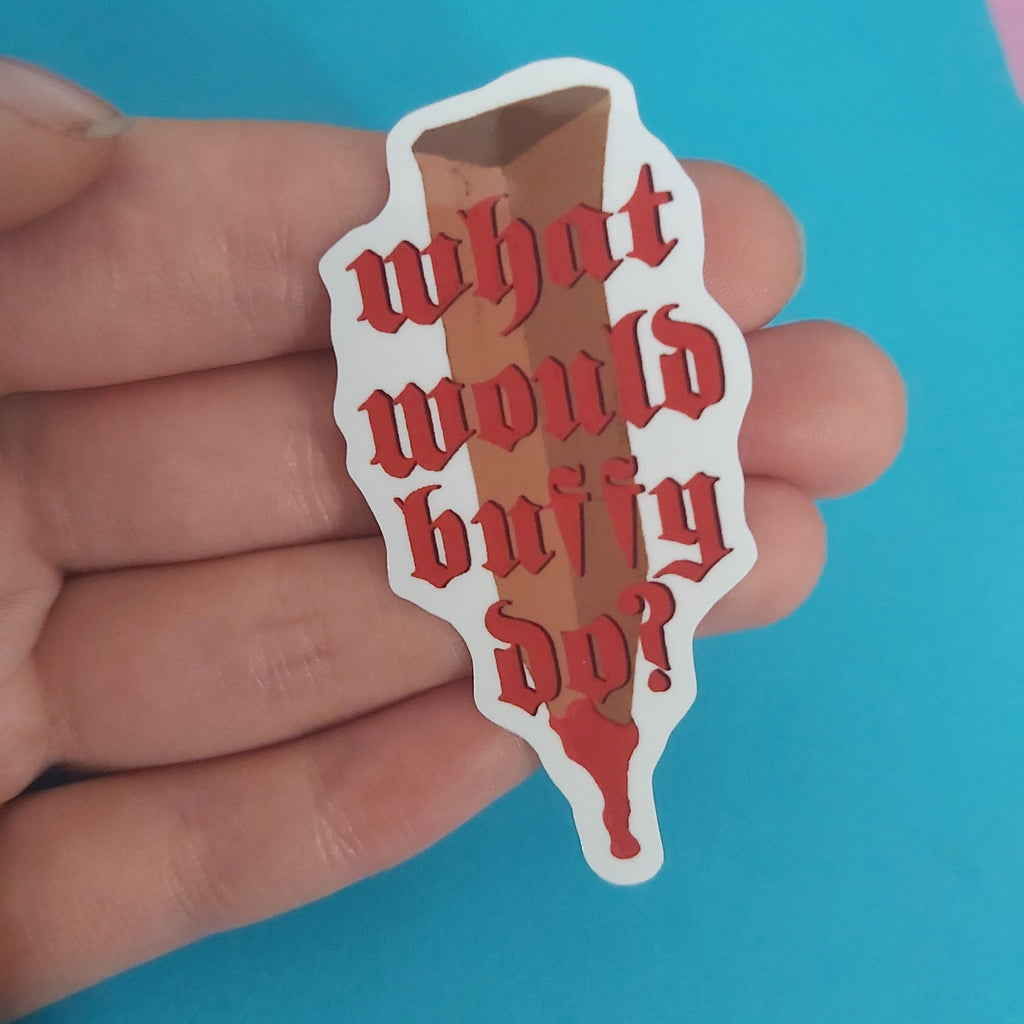 A hand holding a die-cut sticker with red gothic text reading 'what would buffy do?' on a bright blue background.