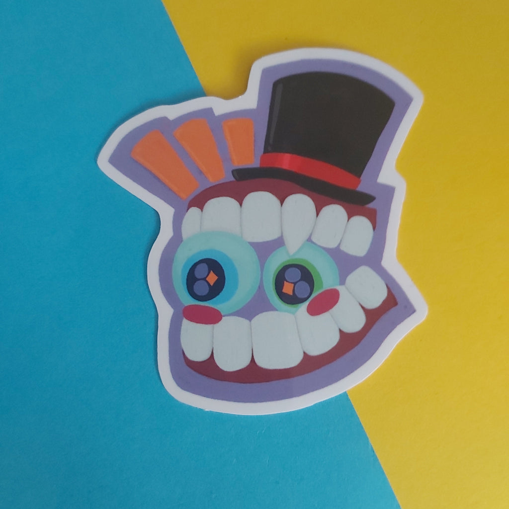 A colorful die-cut sticker featuring a stylized cartoon monster face with large blue eyes, white teeth, a black top hat, and orange accents, placed on a split blue and yellow background.