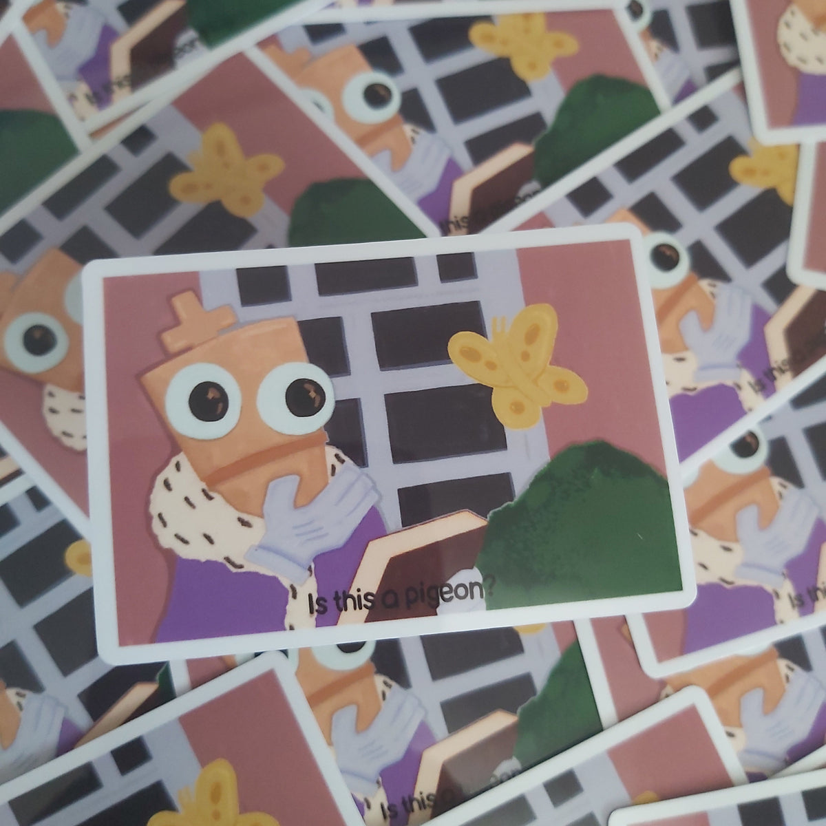 A close-up of a printed sticker featuring a cartoon chess piece character with large eyes and a yellow butterfly, surrounded by a scattered pile of similar stickers.