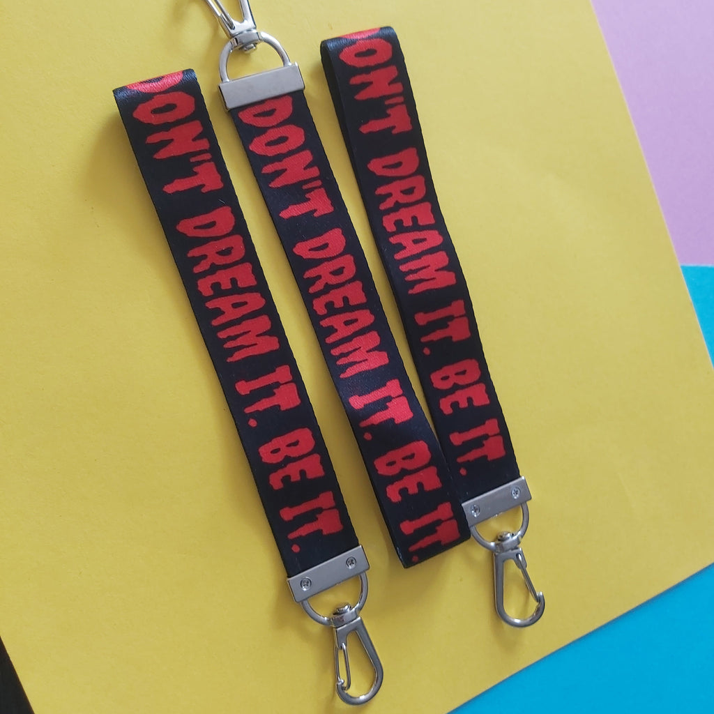 Three black fabric keychains with silver metal clips, featuring the phrase 'DON'T DREAM IT. BE IT.