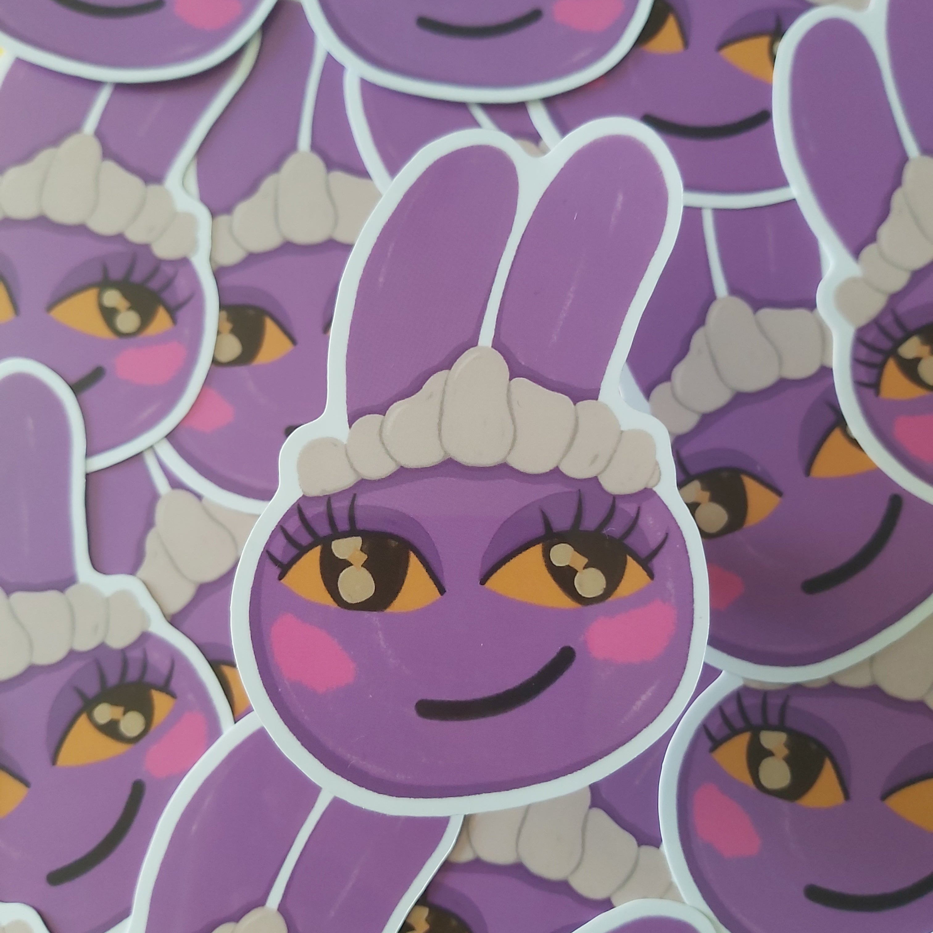 A close-up of multiple purple cartoon bunny Jax stickers with yellow eyes, pink cheeks, and a white maid hat, overlapping each other.