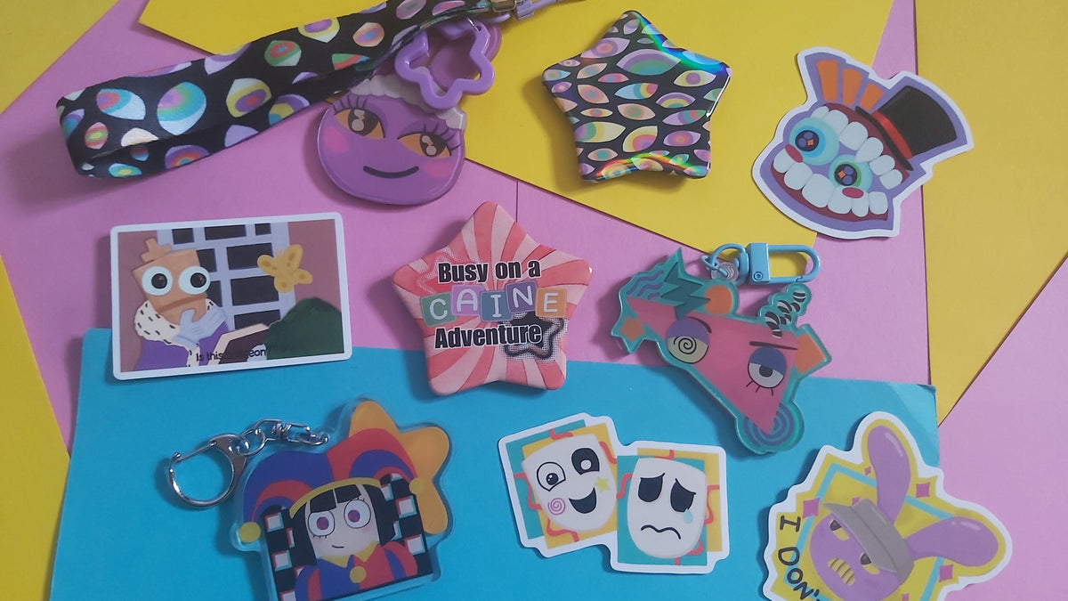 A collection of colorful cartoon-themed keychains and stickers displayed on a bright pink, yellow, and blue geometric background. The set includes a wristlet strap, star-shaped charms, character stickers, and acrylic keychains with various playful expressions.