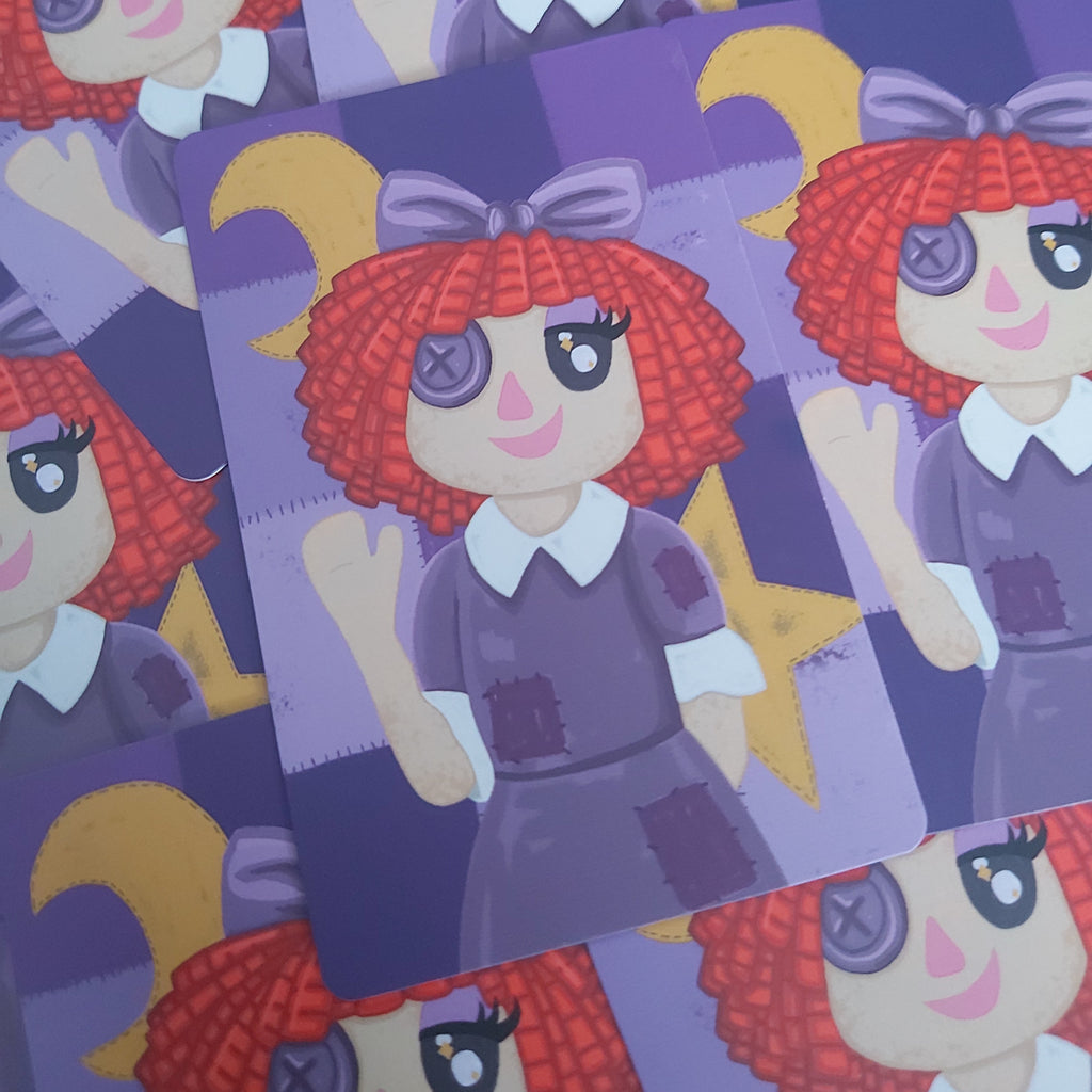 A close-up of several printed card prints featuring a stylized doll character with red curly hair, purple clothing, and a purple bow, arranged on a bright cyan background.