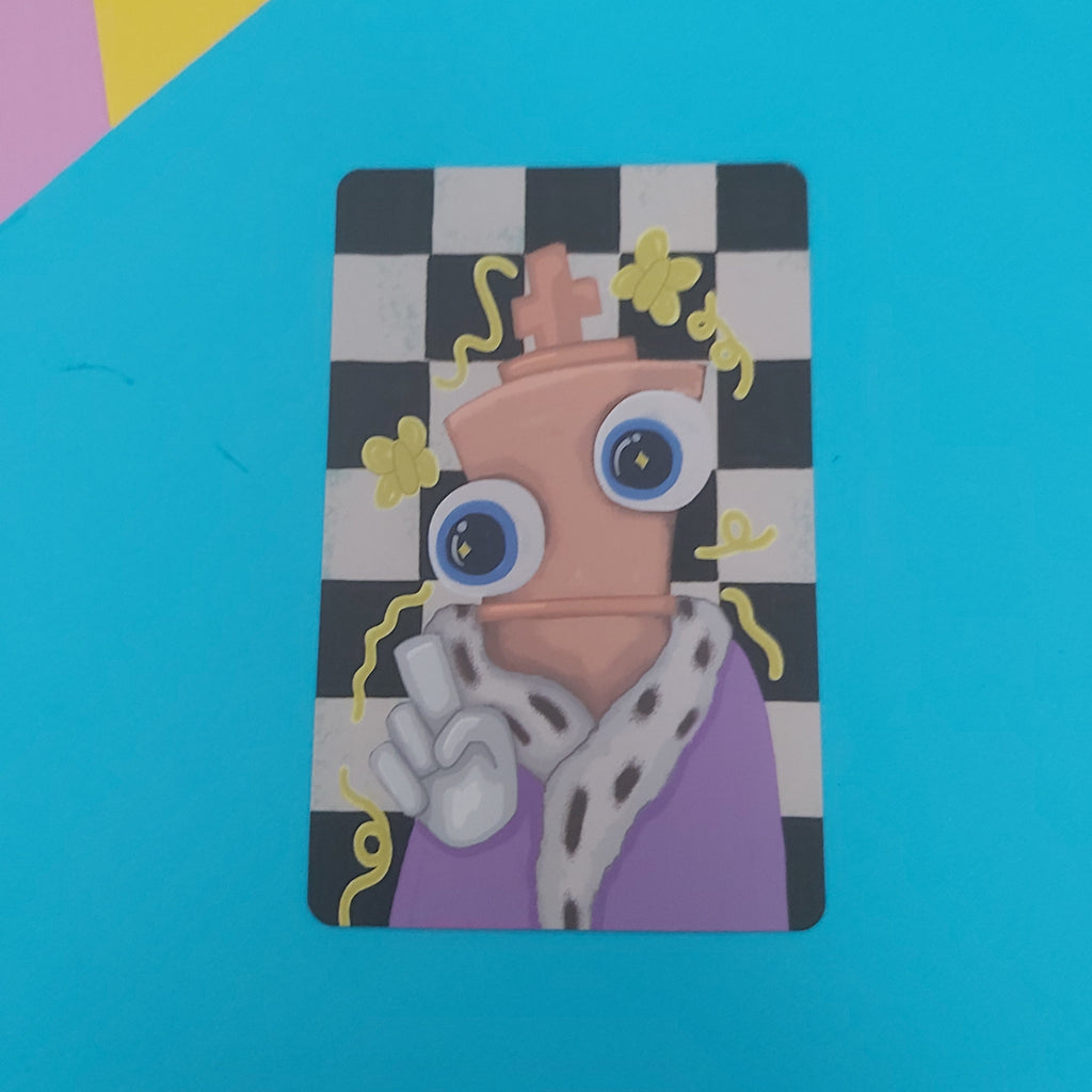 A rectangular art print featuring a stylised cartoon character with large blue eyes, a peach chess piece body, and a purple robe on a black-and-white checkerboard background, placed on a bright blue surface with colourful geometric shapes in the top-left corner.