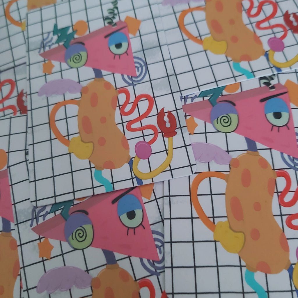 A close-up of patterned craft paper featuring a whimsical character design with a pink triangular head, orange body, blue spiral eyes, and a white grid background.