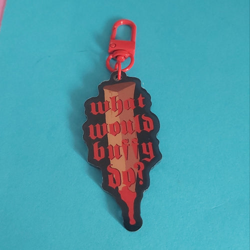 A red and black acrylic keychain charm with the gothic text 'what would buffy do?' printed on it, attached to a red carabiner clip, set against a bright blue background.