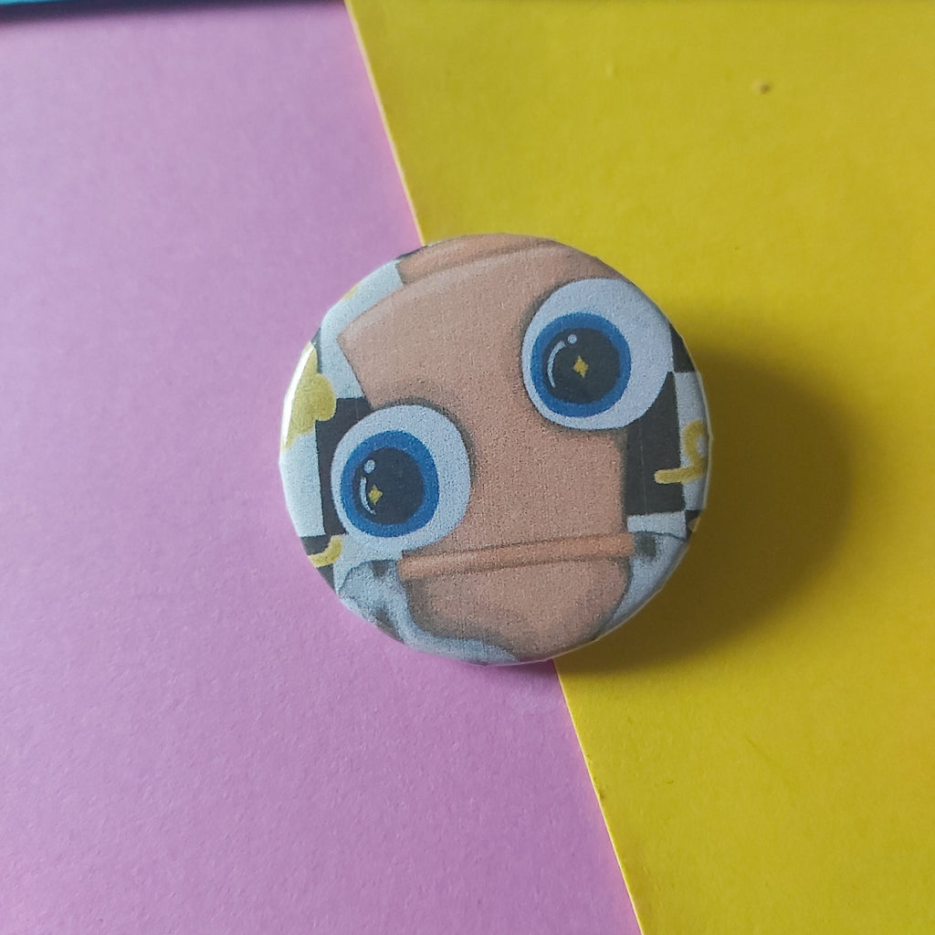 A round pinback button badge featuring a cartoon chess piece face with large blue eyes and a tan head, placed on a diagonally split pink and yellow background.