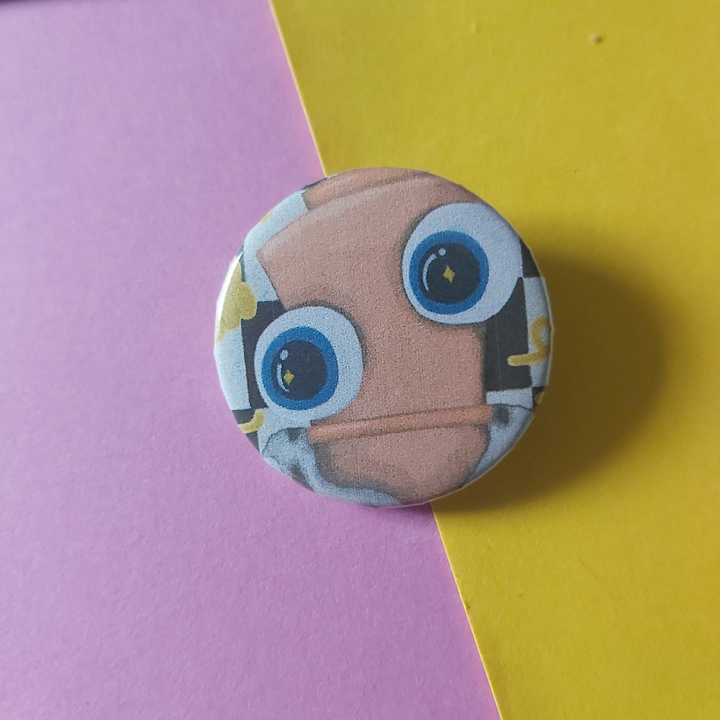 A round pinback button badge featuring a cartoon chess piece face with large blue eyes and a peach-colored face, placed on a diagonally split purple and yellow paper background.