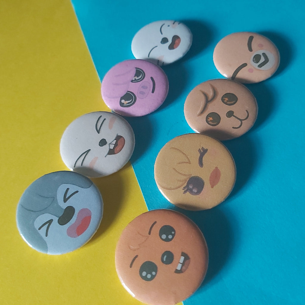 A set of round pinback buttons featuring cartoon animal faces, arranged on a diagonally split yellow and blue background.