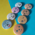 A set of round pinback buttons featuring cartoon animal faces, arranged on a diagonally split yellow and blue background.