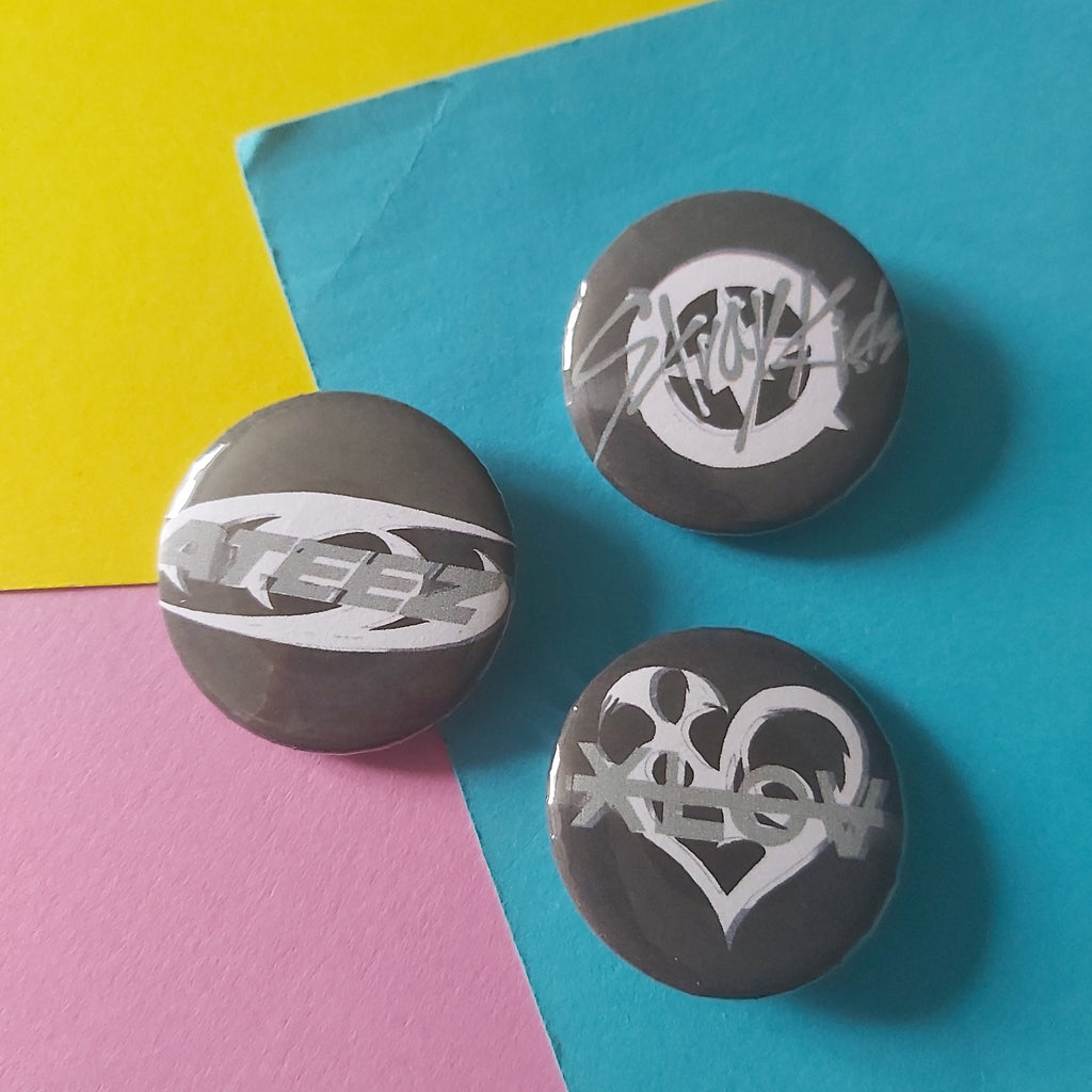 Three round gray button badges with white stylized lettering, arranged on a colorful background split diagonally into yellow, blue, and pink sections.
