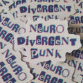 A pile of die-cut stickers featuring the text 'Neuro Divergent Punk' in a stylised purple and blue 3D-effect font on a white background.