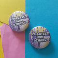 Two round pinback buttons with a pixelated design in purple, white, and yellow, featuring the text 'CHAOTIC NON BINARY' in white. The buttons are displayed on a background split diagonally between yellow and blue, with a pink paper accent on the left.