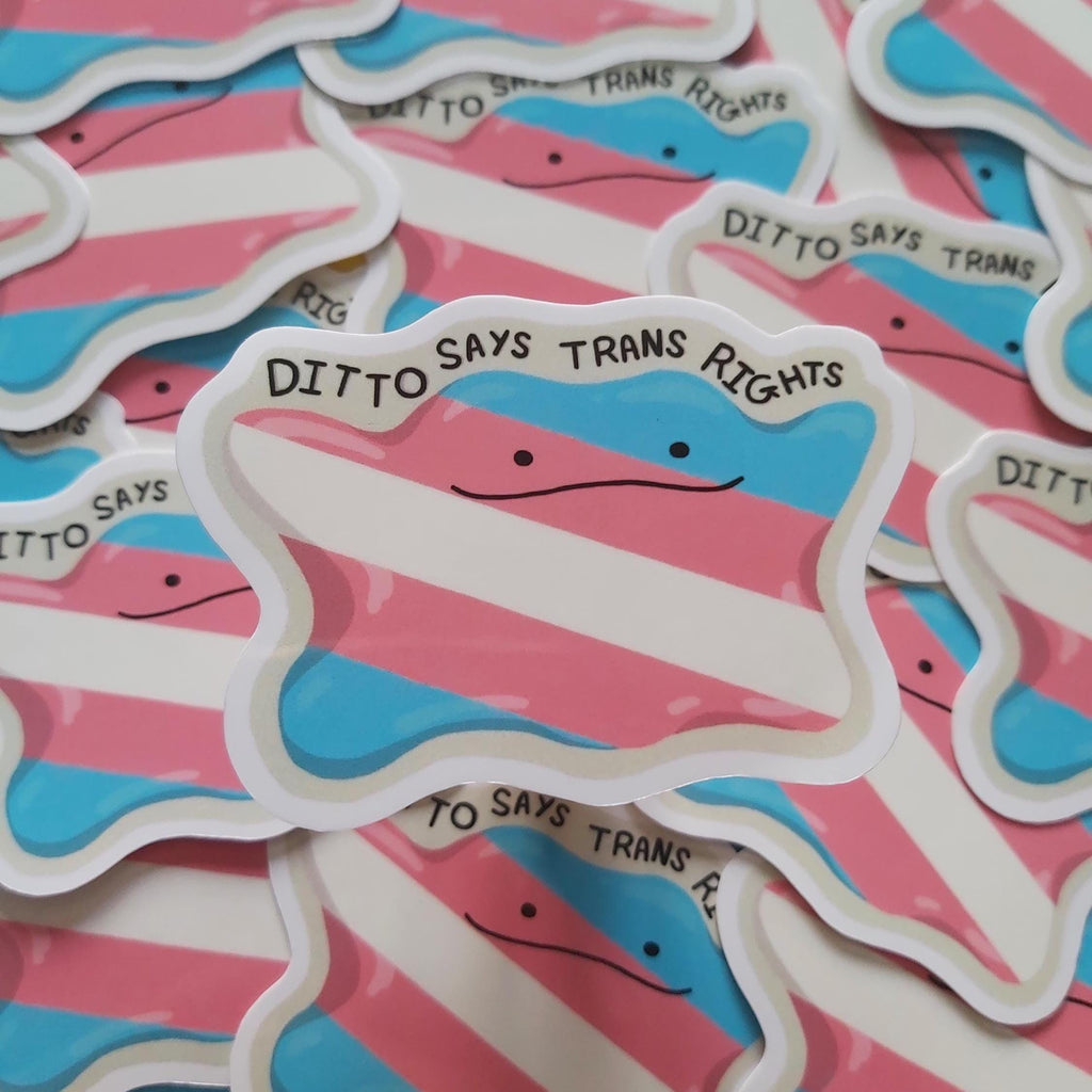 A close-up of multiple die-cut stickers featuring the transgender pride flag with the text 'DITTO SAYS TRANS RIGHTS' and a simple face, arranged overlapping on a white background.