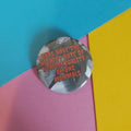A round pinback button badge featuring a grayscale bat photo with red text that reads, 'BATS HAVE THE HIGHEST RATE OF HOMOSEXUALITY AMONG MAMMALS,' placed on a colourful background of cyan, pink, and yellow paper.