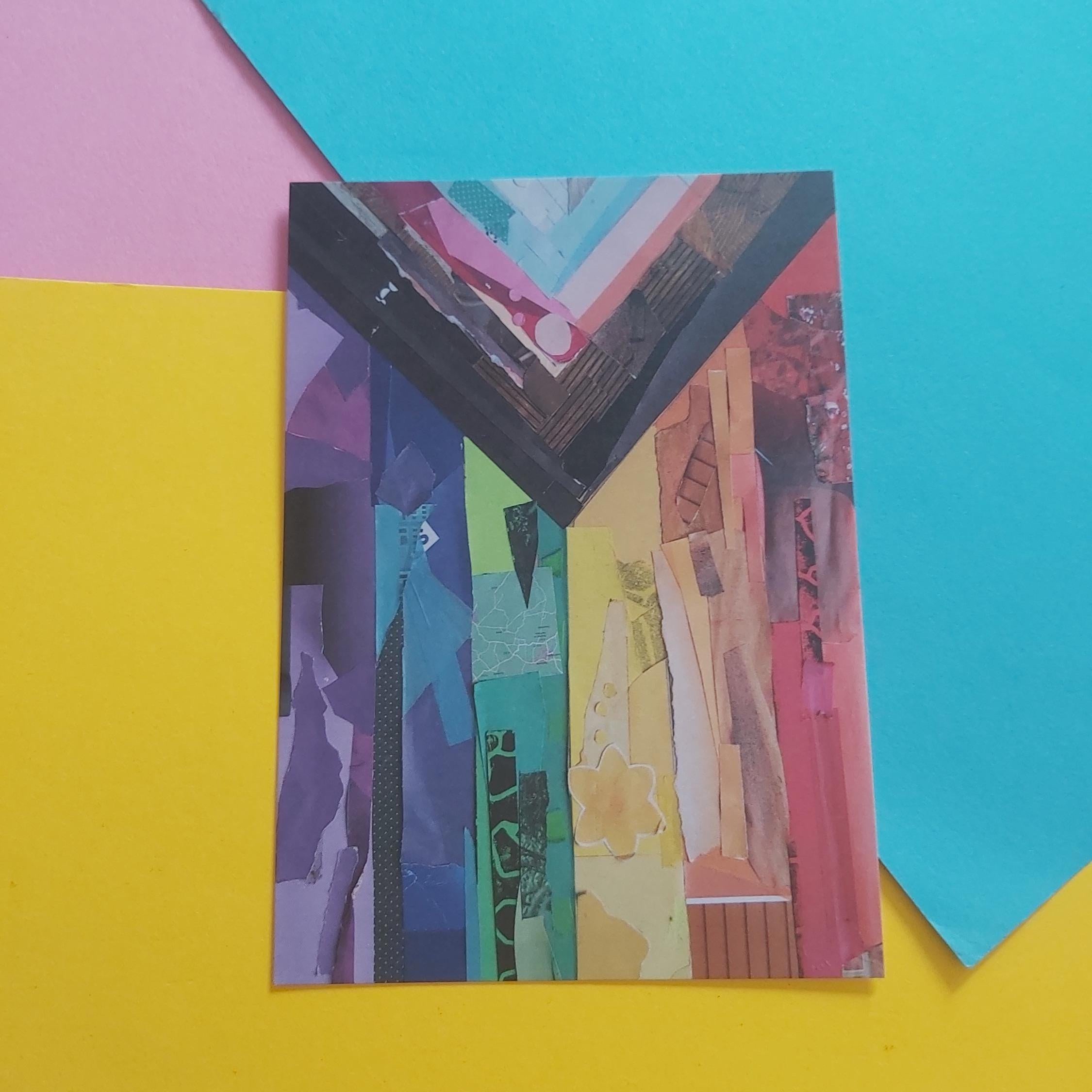 A rectangular art print featuring a colourful collage with vertical textured panels in purple, blue, green, yellow, orange, and pink to create the Progress Pride flag, styled on a background of bright yellow, pink, and blue paper.
