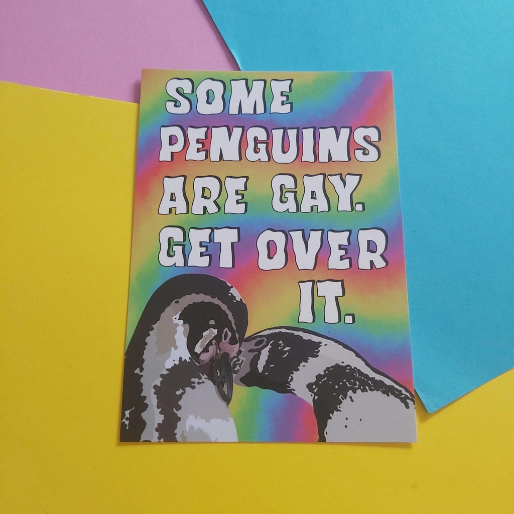A rectangular print with a rainbow gradient background and bold white text reading “SOME PENGUINS ARE GAY.  GET OVER IT. And a penguin couple in the lower left corner