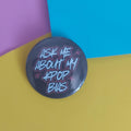 A round pinback button badge with the text 'ASK ME ABOUT MY KPOP BIAS' in stylised white and pink lettering on a dark grey background