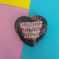 A heart-shaped black with the text 'THREE CHEERS FOR SWEET REVENGE' in white and red, styled with red splatter details, set against a colourful background of pink, yellow, and blue paper.