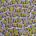 A pile of die-cut stickers featuring the text 'Team Enbya' in bold yellow letters with a purple outline on a white background.