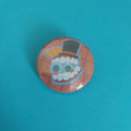 A round pinback button featuring a cartoon character with a top hat, set against a red background.