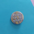 A round pinback button badge featuring a yellow and purple marbled pattern with the text 'Chaos has no gender' in white letters, displayed on a bright blue background.