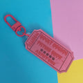 A pink ticket-shaped keychain with a red carabiner clip, featuring the text 'ROCKY HORROR PICTURE SHOW ADMIT ONE' on a split blue, pink, and yellow background.