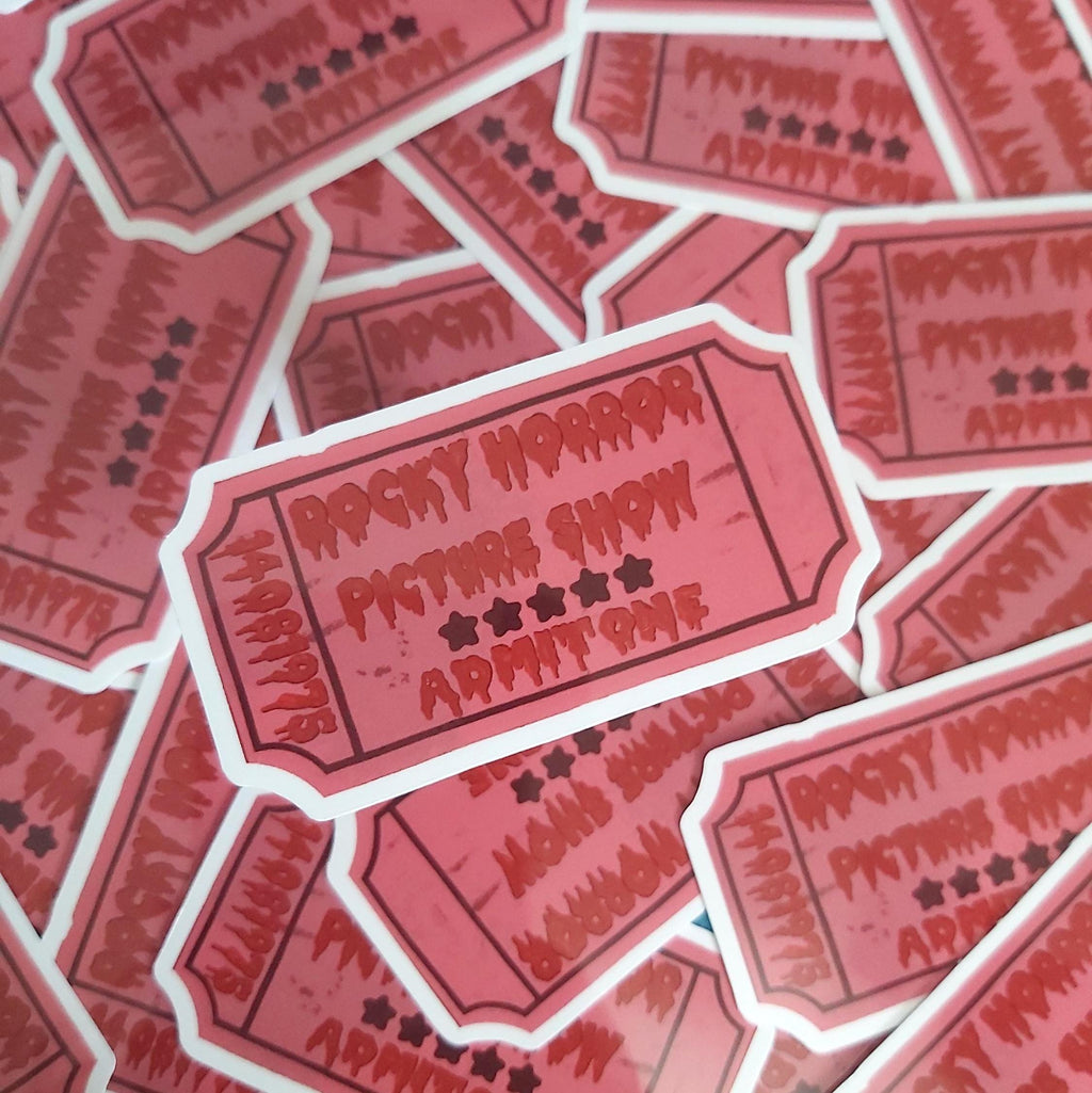 A pile of die-cut stickers shaped like vintage movie tickets, featuring the text 'ROCKY HORROR PICTURE SHOW ADMIT ONE' in a distressed red font on a pink background with white borders.